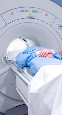 A patient in a hospital gown lying inside an MRI scanner.