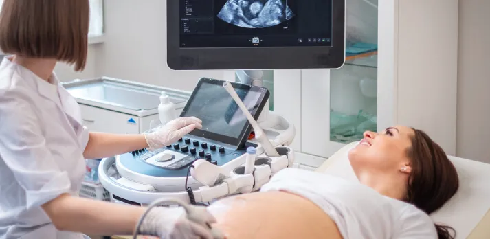 A doctor performing an ultrasound on a pregnant woman in a clinic.