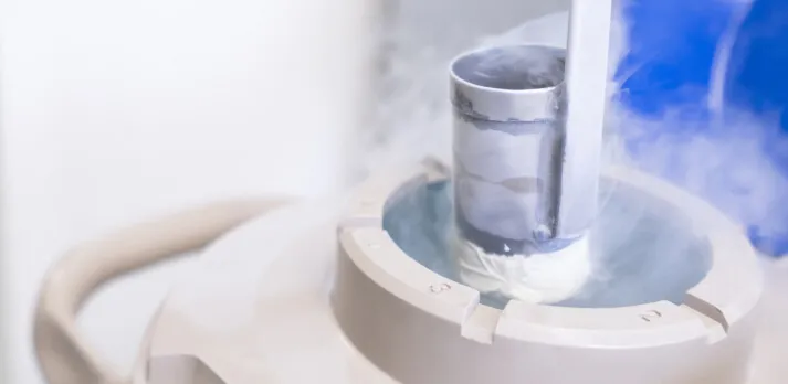 A cryogenic storage tank releasing vapor, used for freezing and storing biological samples.