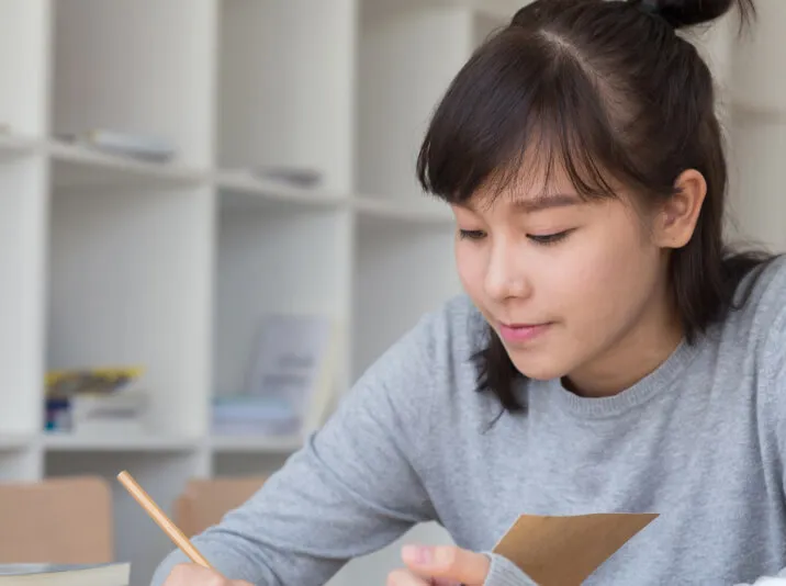 A young woman writing notes at a desk.